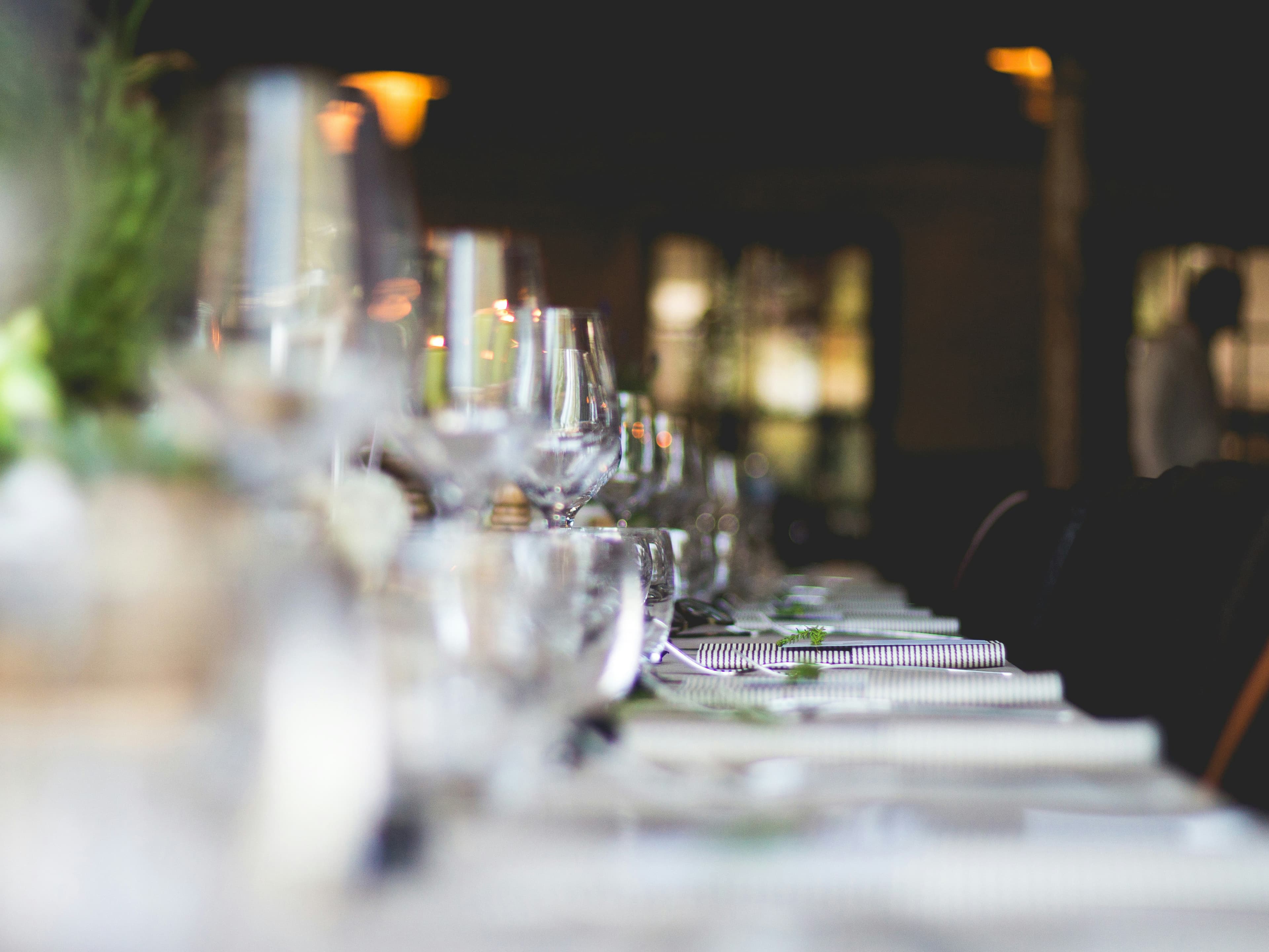 Elegant table setting for an event at Hotel Conte, with neatly arranged glassware and a soft focus on the ambient lighting in the background.