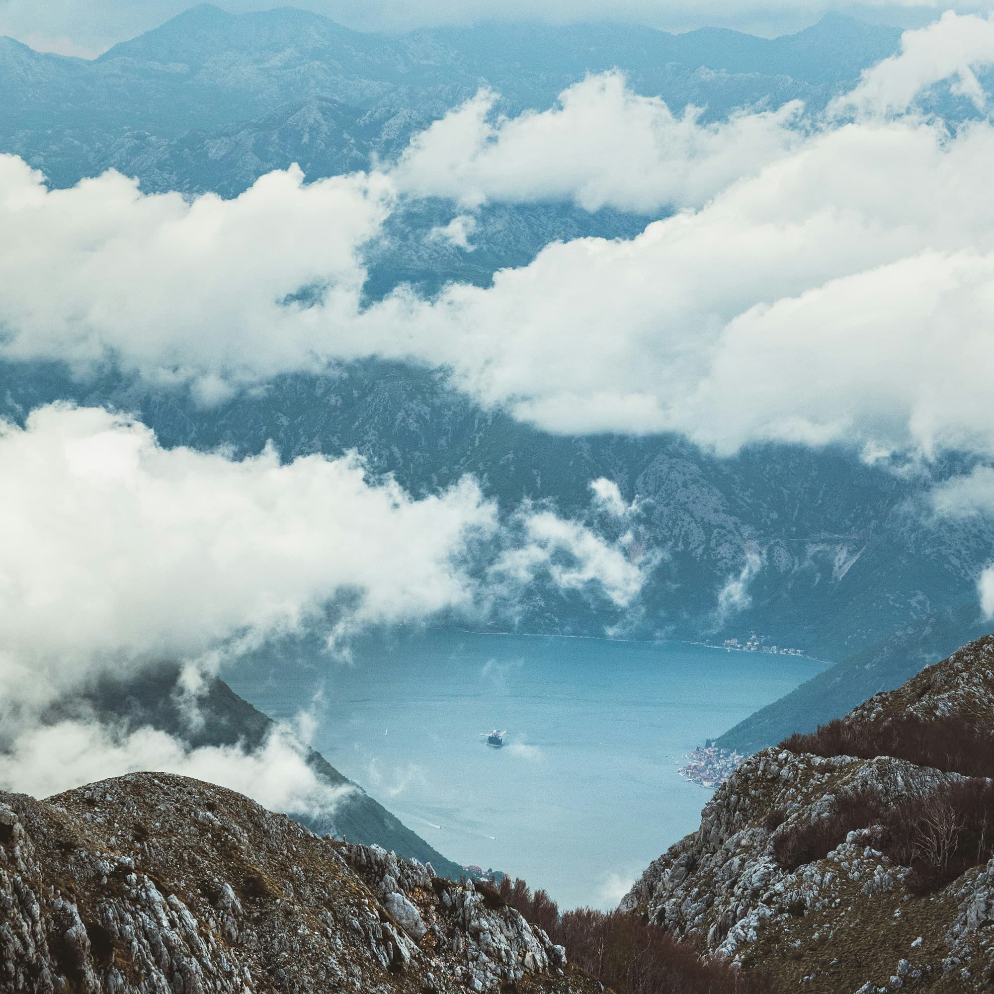 Clouds hovering over a mountainous landscape with a view of Kotor Bay below.