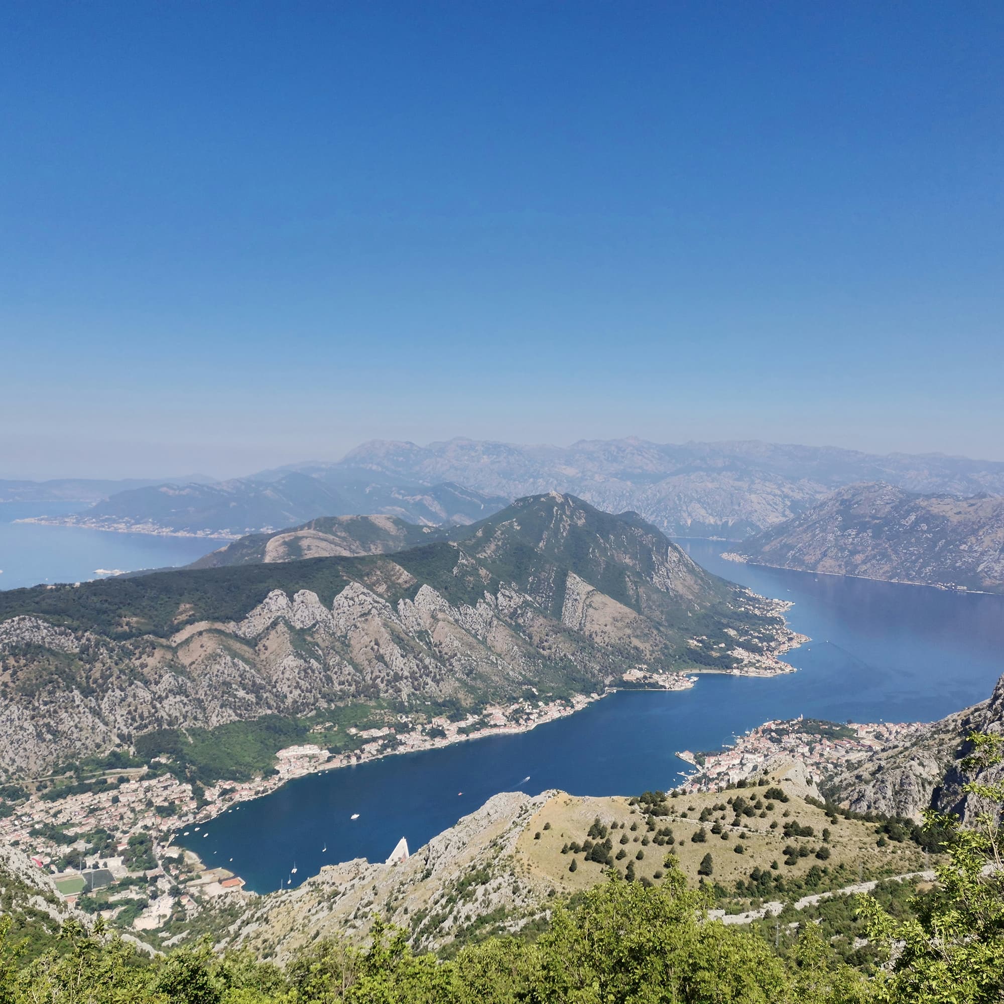 Aerial view of Kotor Bay, surrounded by mountains and dotted with small coastal towns.