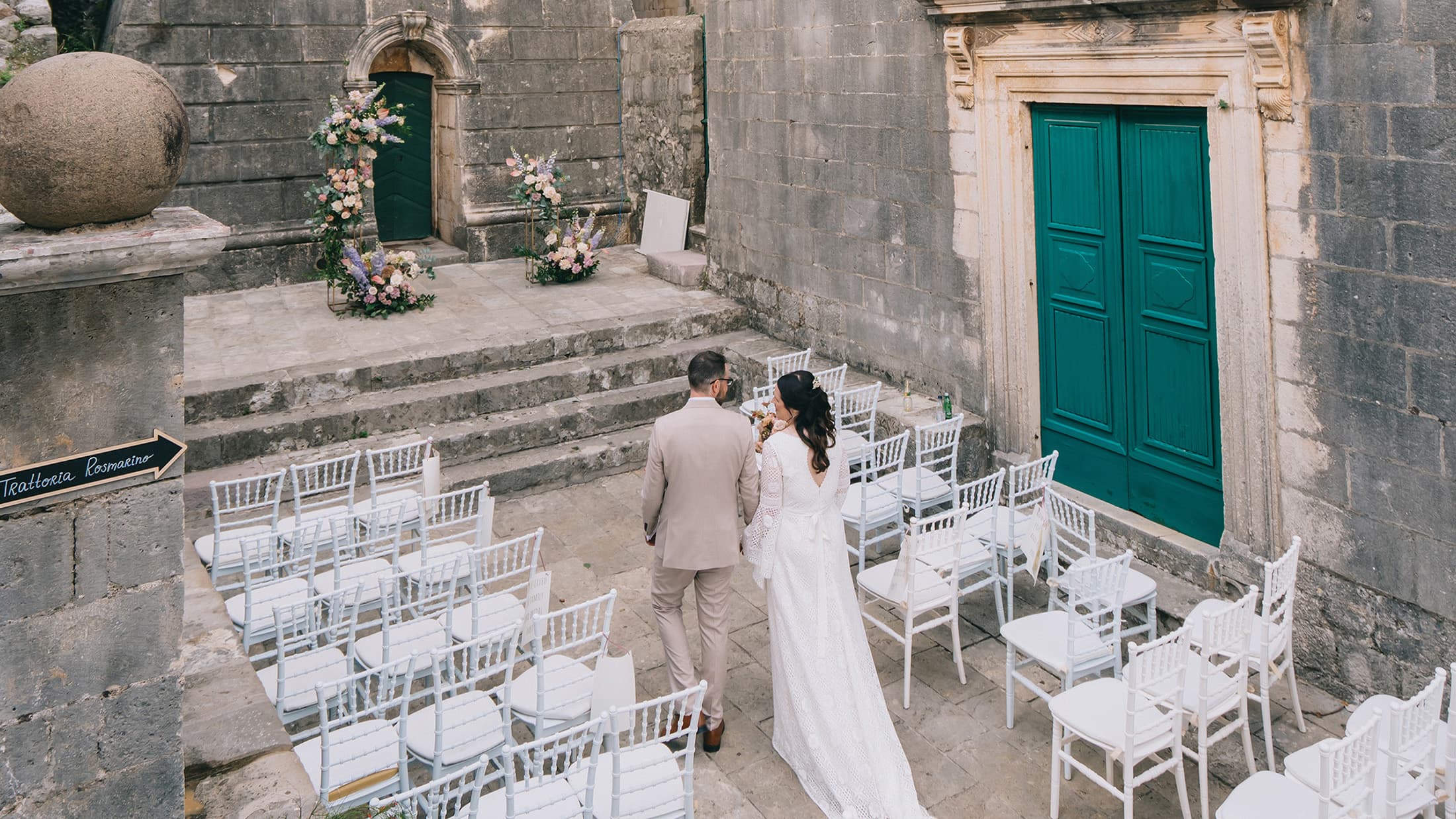 Bride and groom walking through the terrace in the old square, holding hands.