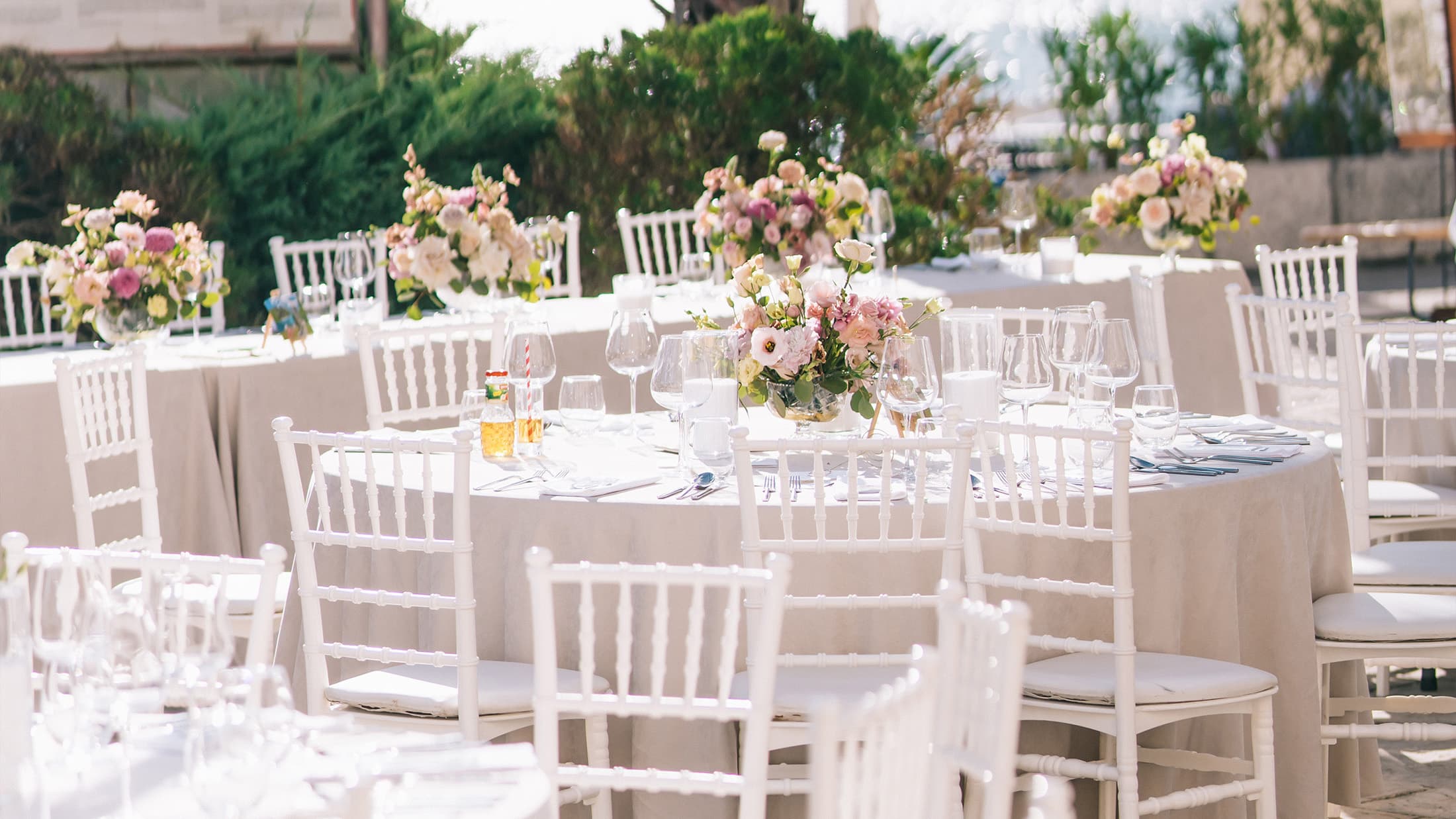 White tables with cutlery and floral arrangements.