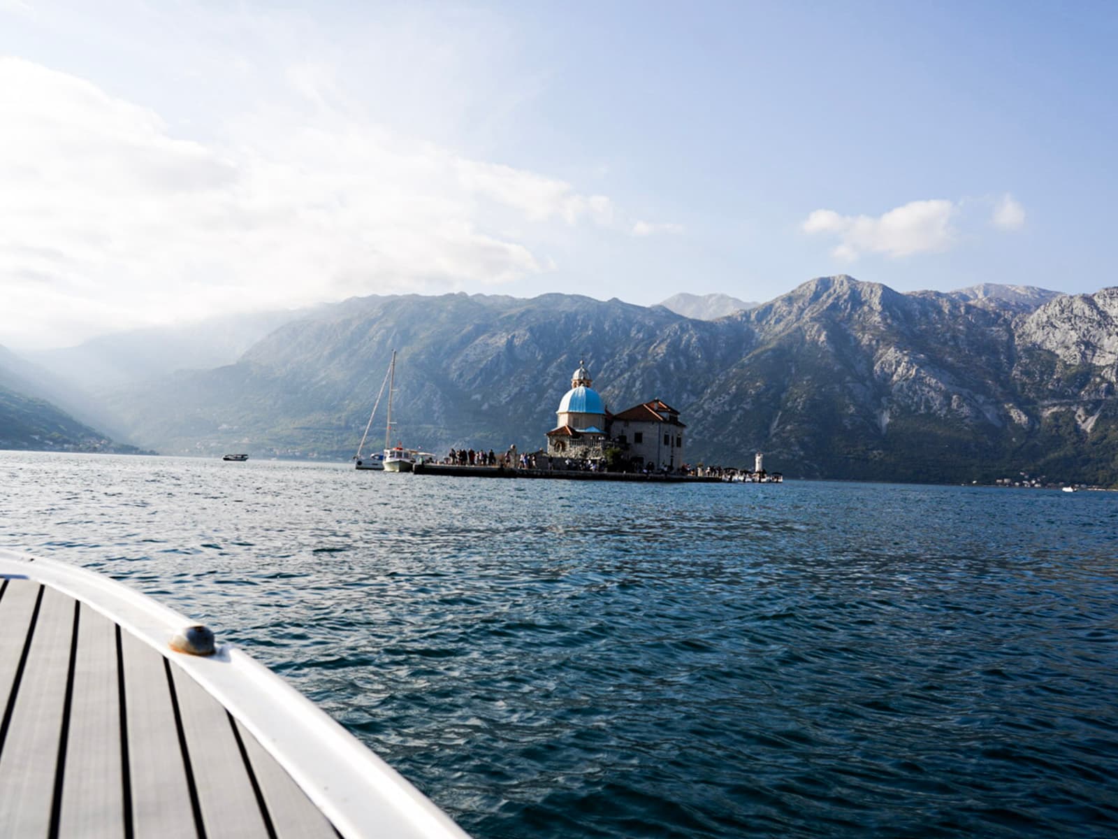 Glass of white wine and a bottle of Conte Cuvée on a table with a plate of oysters, set against the backdrop of the Bay of Kotor at Hotel Conte's restaurant.