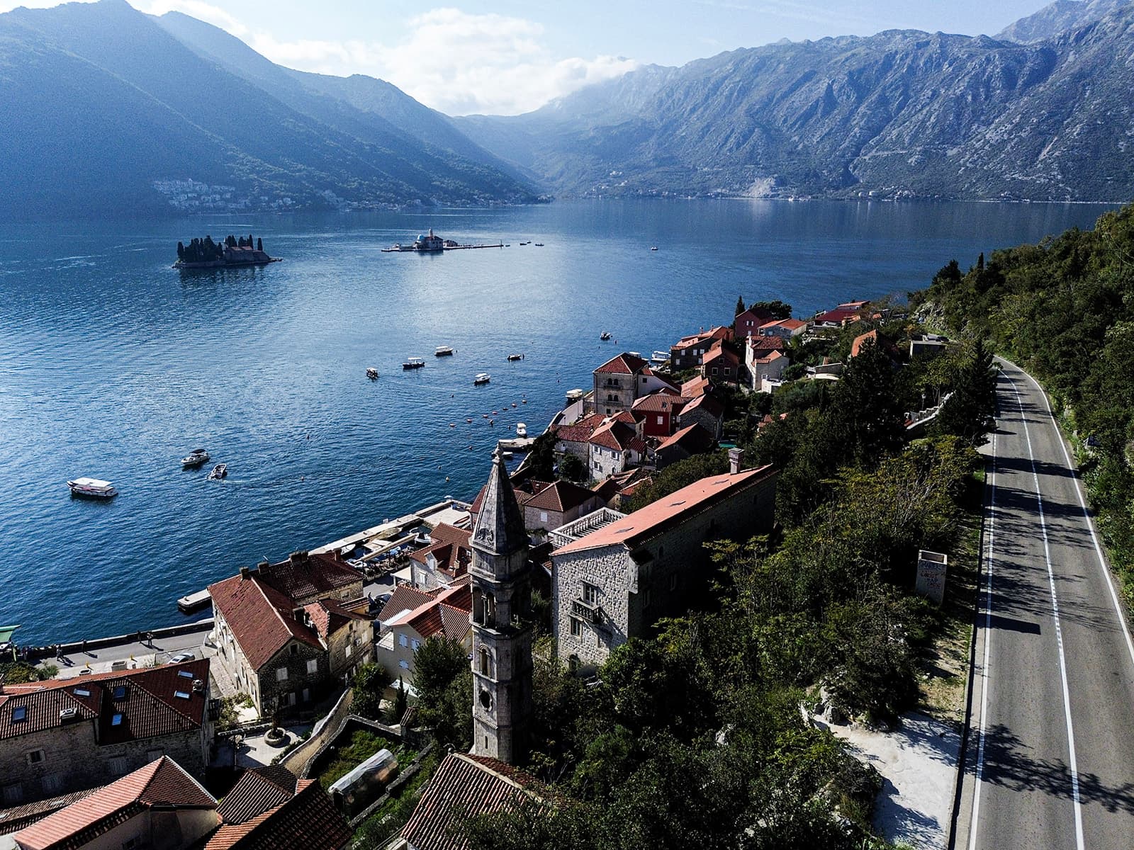 Delicious seafood dishes at Hotel Conte's restaurant, featuring a platter of prawns, scallops, and rice with a side of cheese and cured meats, enjoyed by a guest overlooking the Bay of Kotor.