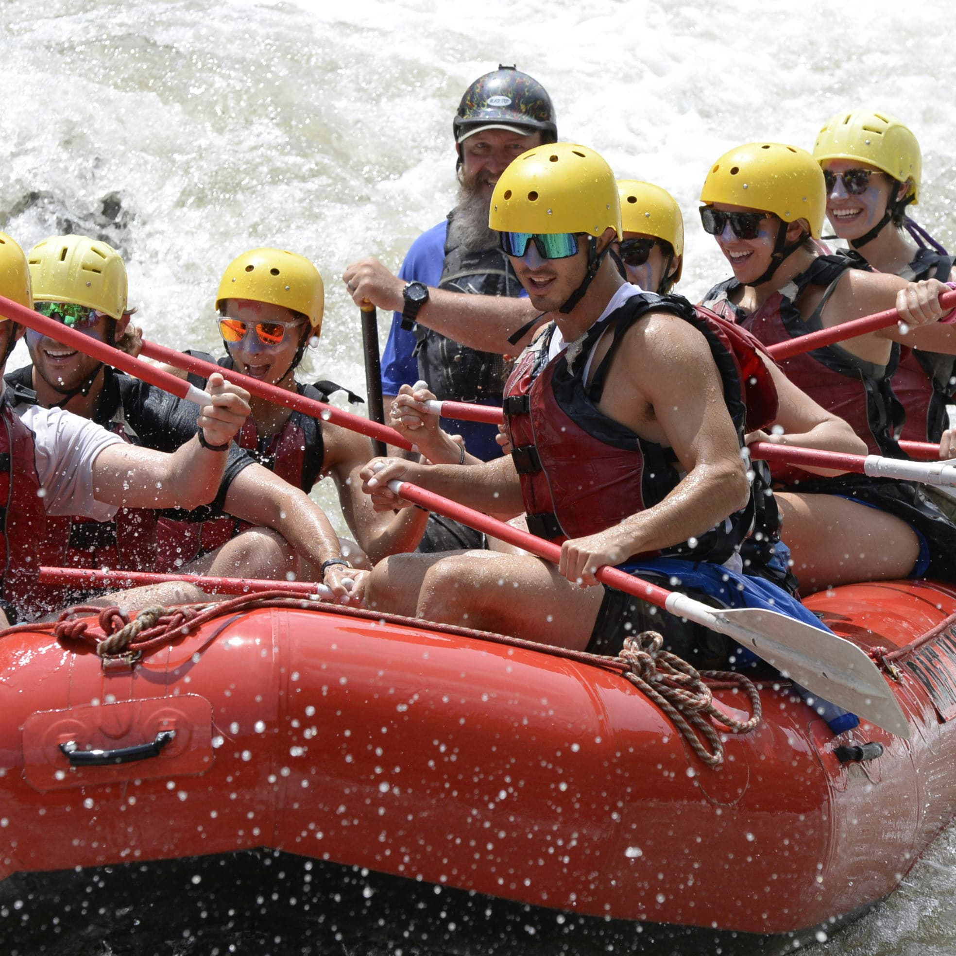 Group of people white water rafting on the Tara River, wearing helmets and life vests.